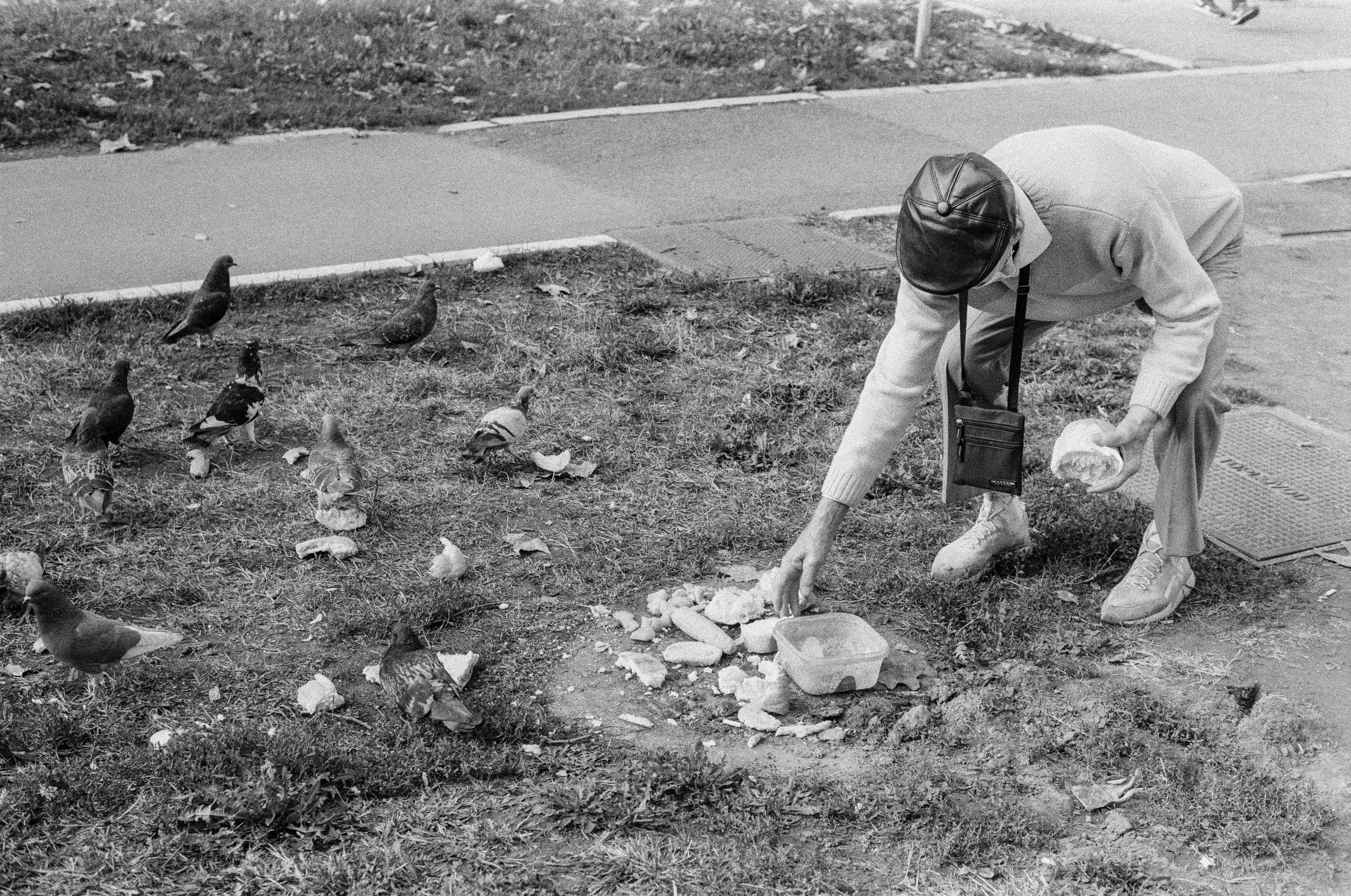 grayscale photo of man in t-shirt and shorts holding garbage bag